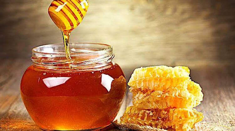 jar of honey with honeycomb on wooden table