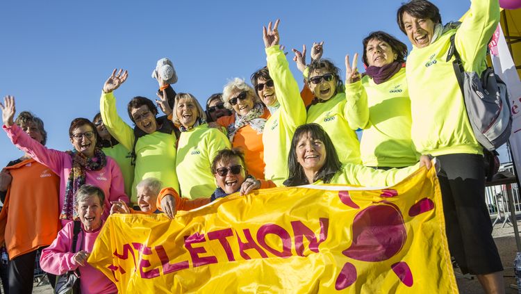 Un groupe de femmes portant une banderole du Téléthon.