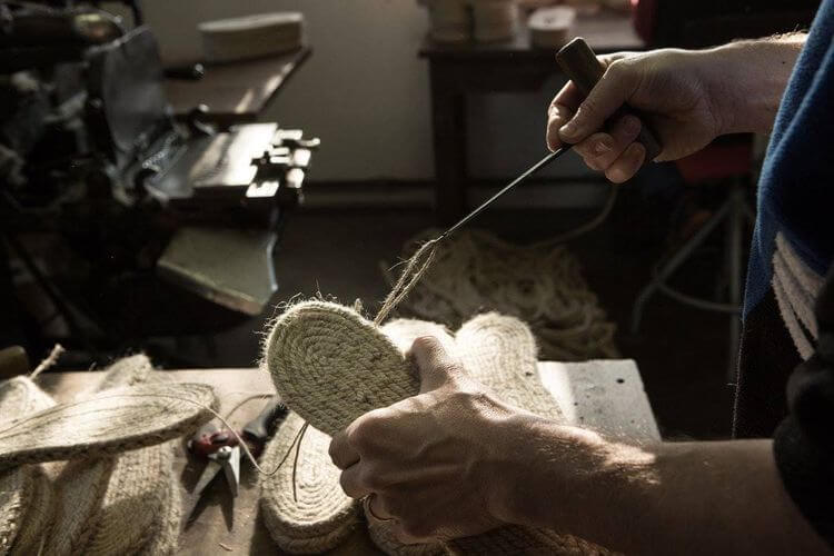 Un artisan qui noue la semelle d'une espadrille à Chéraute, dans les ateliers de Zétoiles.