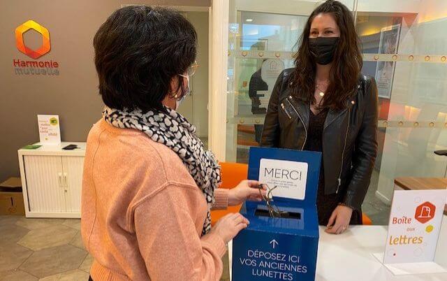 Une dame dépose une paire de lunettes dans une boite à cet effet, dans une agence Harmonie Mutuelle.