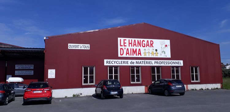 Une photo de la façade d'un hangar de l'association AIMA.