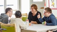 Une bénévole d'Ekin joue à un jeu de société avec des jeunes personnes atteintes de handicap.