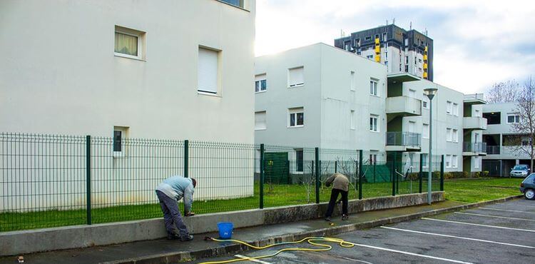 Des travailleurs nettoie une clôture à Tarbes dans le cadre des missions du Comptoir de Services.