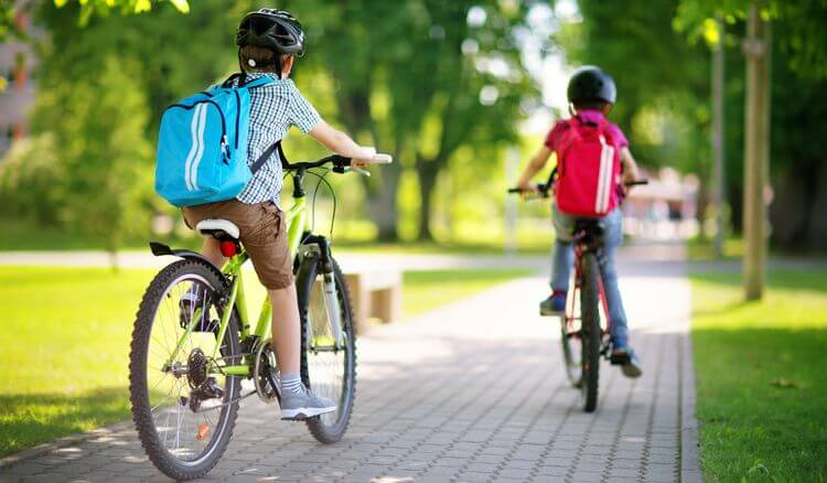 Deux enfants font du vélo sur un trottoir.