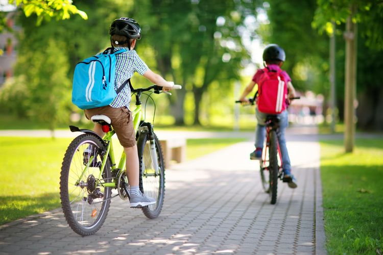 Deux enfants font du vélo sur un trottoir.