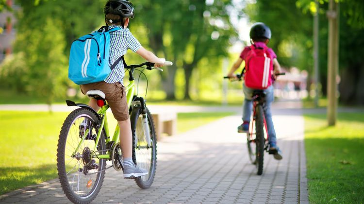 Deux enfants font du vélo sur un trottoir.