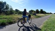 Une jeune femme fait du vélo sur une petite route de campagne.