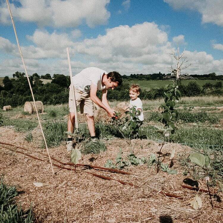 Un producteurs travaille dans un champs avec un enfant.