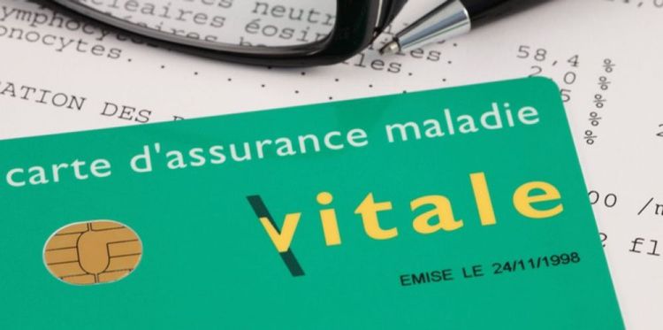 Une carte vitale posée sur une fiche de renseignement de santé.
