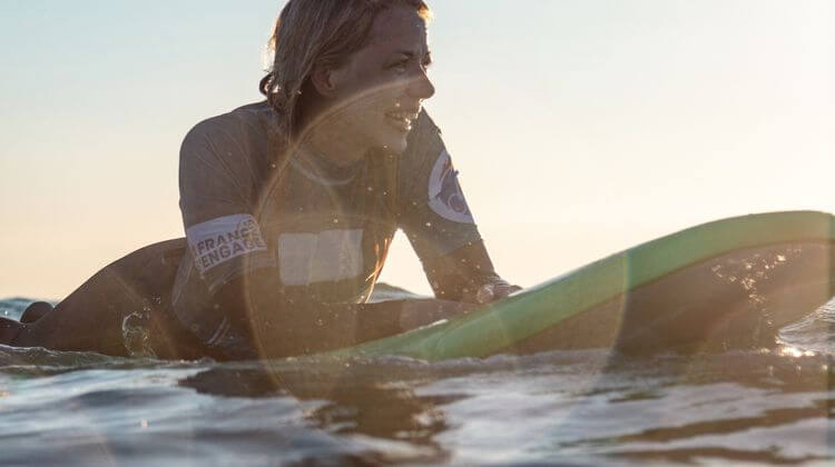 Une jeune femme membre de l'association Handisurf en mer, sur une planche de surf.