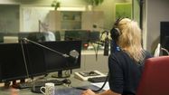 Une femme anime une radio depuis un studio d'enregistrement.
