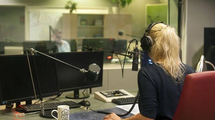 Une femme anime une radio depuis un studio d'enregistrement.