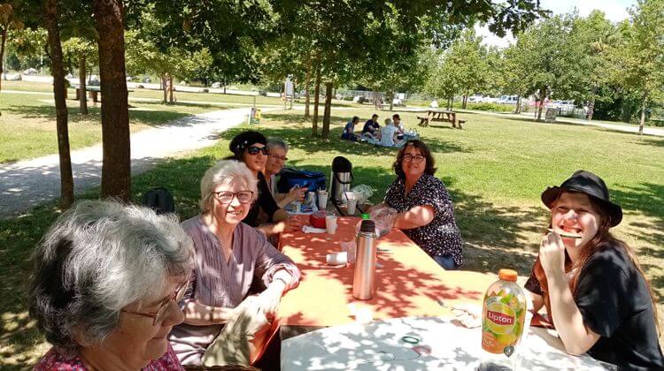 Des membres de l'Accorderie de Pau mangent dans un parc.