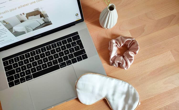 Un masque et un chouchou en soie sont posé sur une table, devant un ordinateur ouvert sur le site internet de la Maison de la Soie.