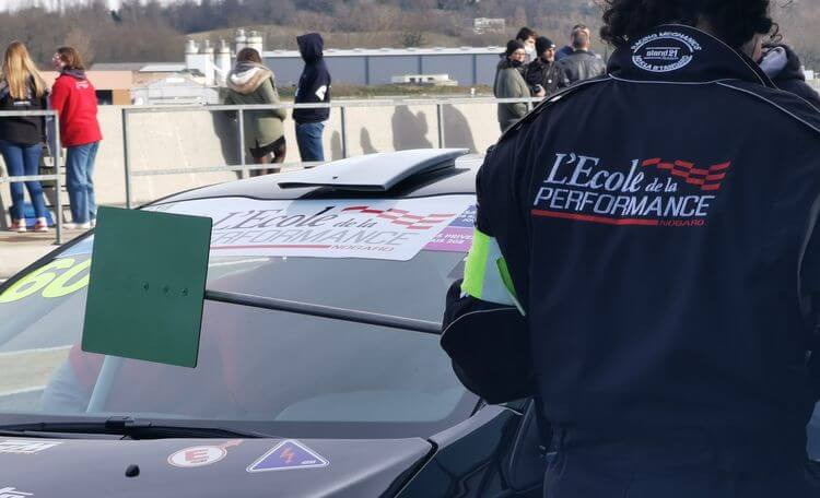 Un stagiaire de l'école de la Performance indique à un pilote de s'arrêter dans les stands.