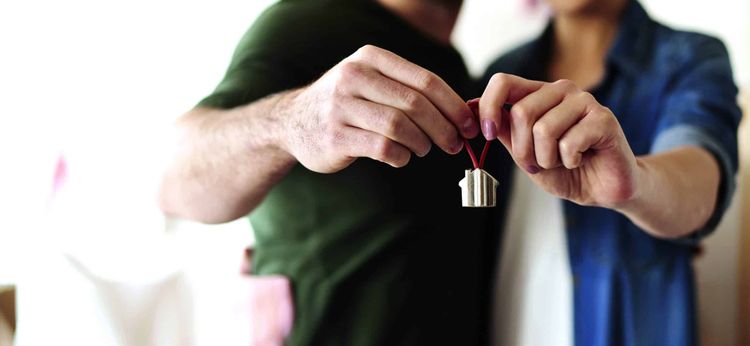Un couple tient un porte-clé représentant une maison.