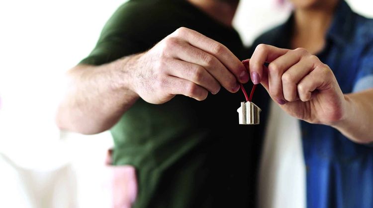 Un couple tient un porte-clé représentant une maison.