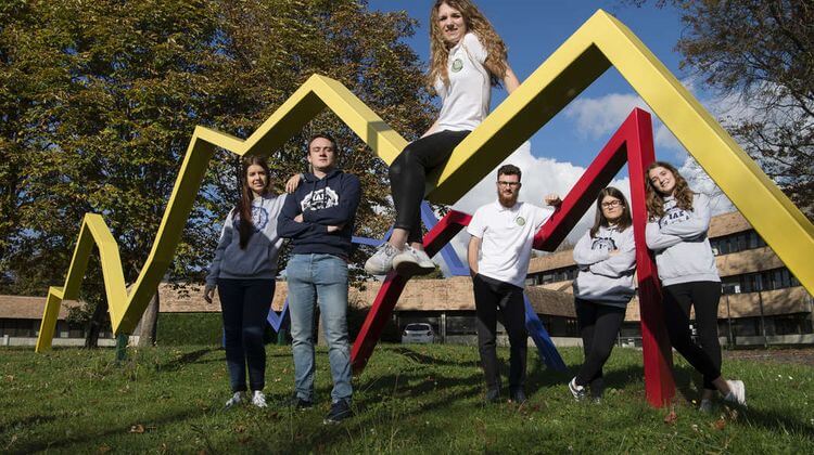 Des élèves de l'IAE Pau-Bayonne posent sur des structures métalliques colorées devant le campus de Pau.