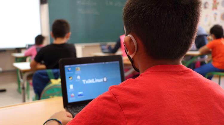 Un enfants est en classe avec un ordinateur équipé du programme d'exploitation Txikilinux.