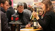 Des visiteurs dégustent une bouteille de vin rouge lors du salon Aux Vignobles de Biarritz.