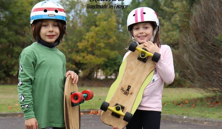 Deux enfants tenant dans leurs mains deux planches de skateboard Parabolik.