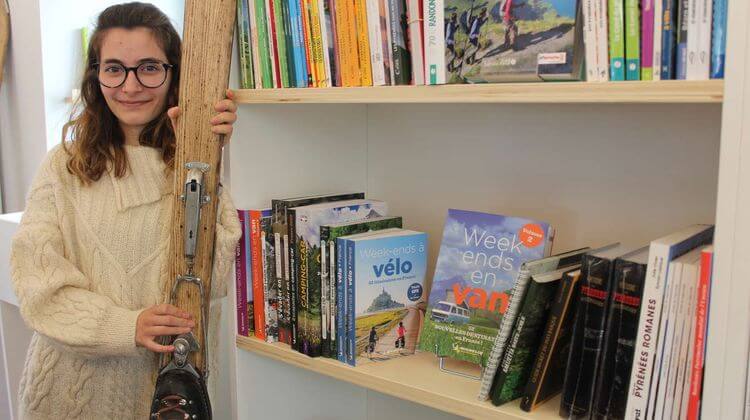 La Libraire de 22 ans Charlène Bats devant une étagère de la nouvelle librairie de la Ciutat, à Pau.