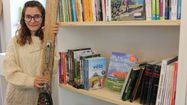 La Libraire de 22 ans Charlène Bats devant une étagère de la nouvelle librairie de la Ciutat, à Pau.