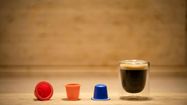 Une tasse de café posée sur une table et ses 3 capsules en exposition