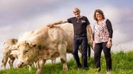 Betty et Philippe Villas dans un champ devant leur troupeau de vaches