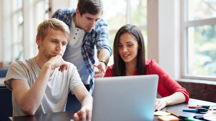 Des jeunes étudiants travaillent ensemble sur un ordinateur portable.