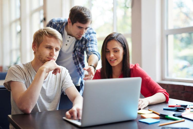 Des jeunes étudiants travaillent ensemble sur un ordinateur portable.