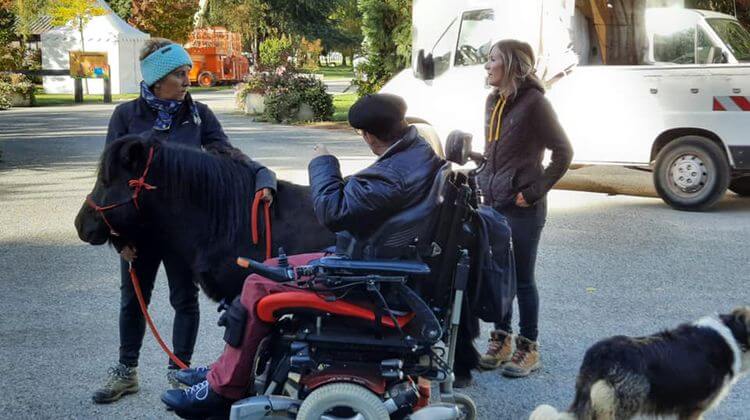 Une personne en situation de handicap est accompagnée par Claire Rondet et Sonia Everaere et un poney.