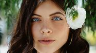 Portrait d'une jeune femme aux yeux bleus avec une fleur blanche sur l'oreille