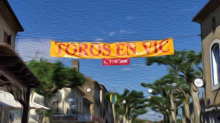 Photo d'une banderole suspendue entre deux maisons avec l'inscription "Toros en Vic"