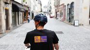 Livreur vu de dos sur un vélo transportant les marchandises dans les rues de Pau