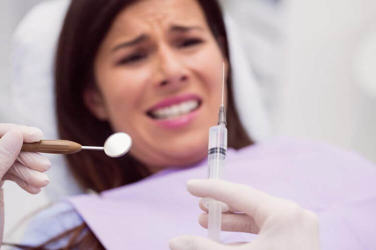Dentiste s'apprêtant à piquer une patiente inquiète