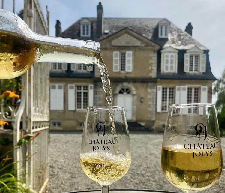 Les vins blancs du Château Jolys avec le domaine en arrière plan.