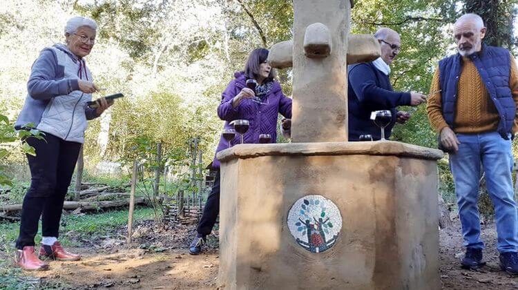 Des membres de l'association Deux Mains la Terre partagent un moment convivial autour de la fontaine du jardin.