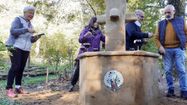 Des membres de l'association Deux Mains la Terre partagent un moment convivial autour de la fontaine du jardin.