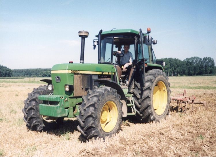 Un agriculteur dans son tracteur en train de cultiver son champ.
