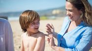 Une mère étale de la crème solaire sur son fils à la plage.