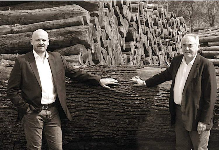 Deux membres de la famille Canadell devant des troncs d'arbres de chêne.