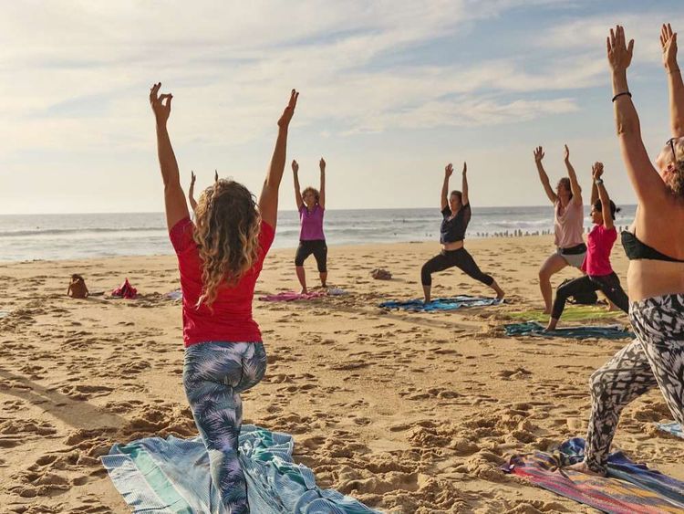 Des femmes pratiquent le yoga sur la plage de Seignosse dans les Landes dans le cadre des Expériences Nature.