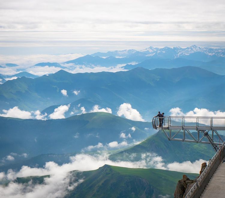 Deux personnes profitent de la vue au-dessus du vide au sommet du Pic du Midi.