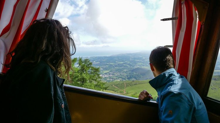 Deux personnes profitent de la vue à bord du train de la Rhune au Pays basque.