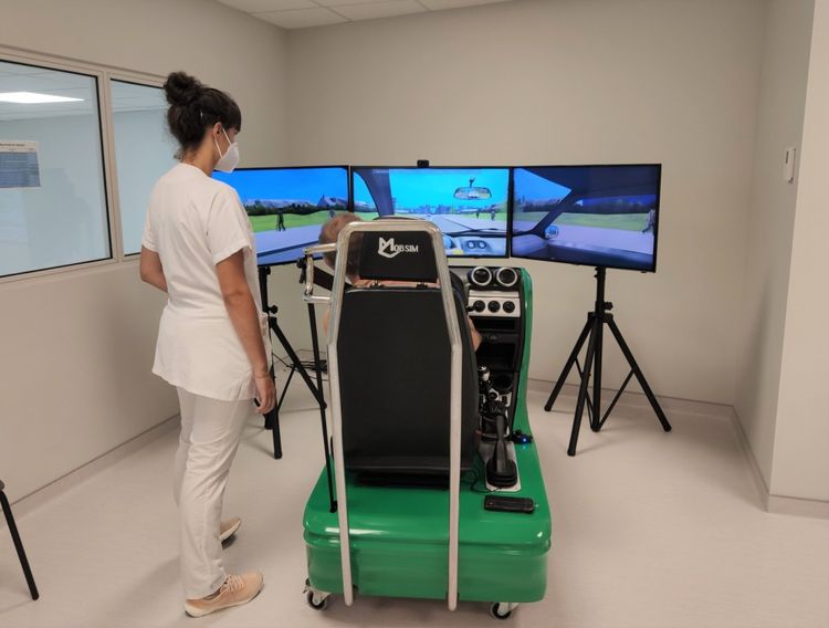 Photo d'une personne s'installant dans le simulateur de conduite avec un soignant