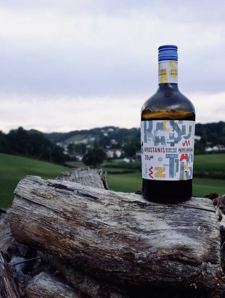 Une bouteille de Noustanis avec en fond les vallées du Béarn.