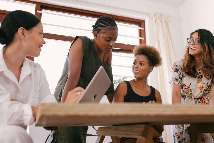 Quatre femmes discutent autour d'une table.
