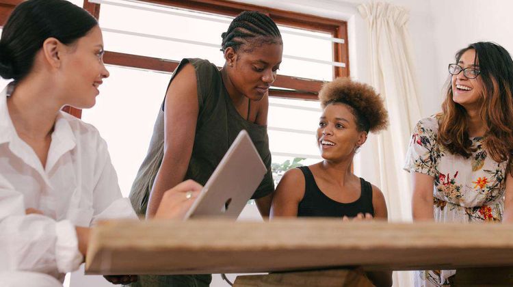 Quatre femmes discutent autour d'une table.