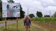 Photo de Jean-Luc Garroussia à coté du panneau du domaine